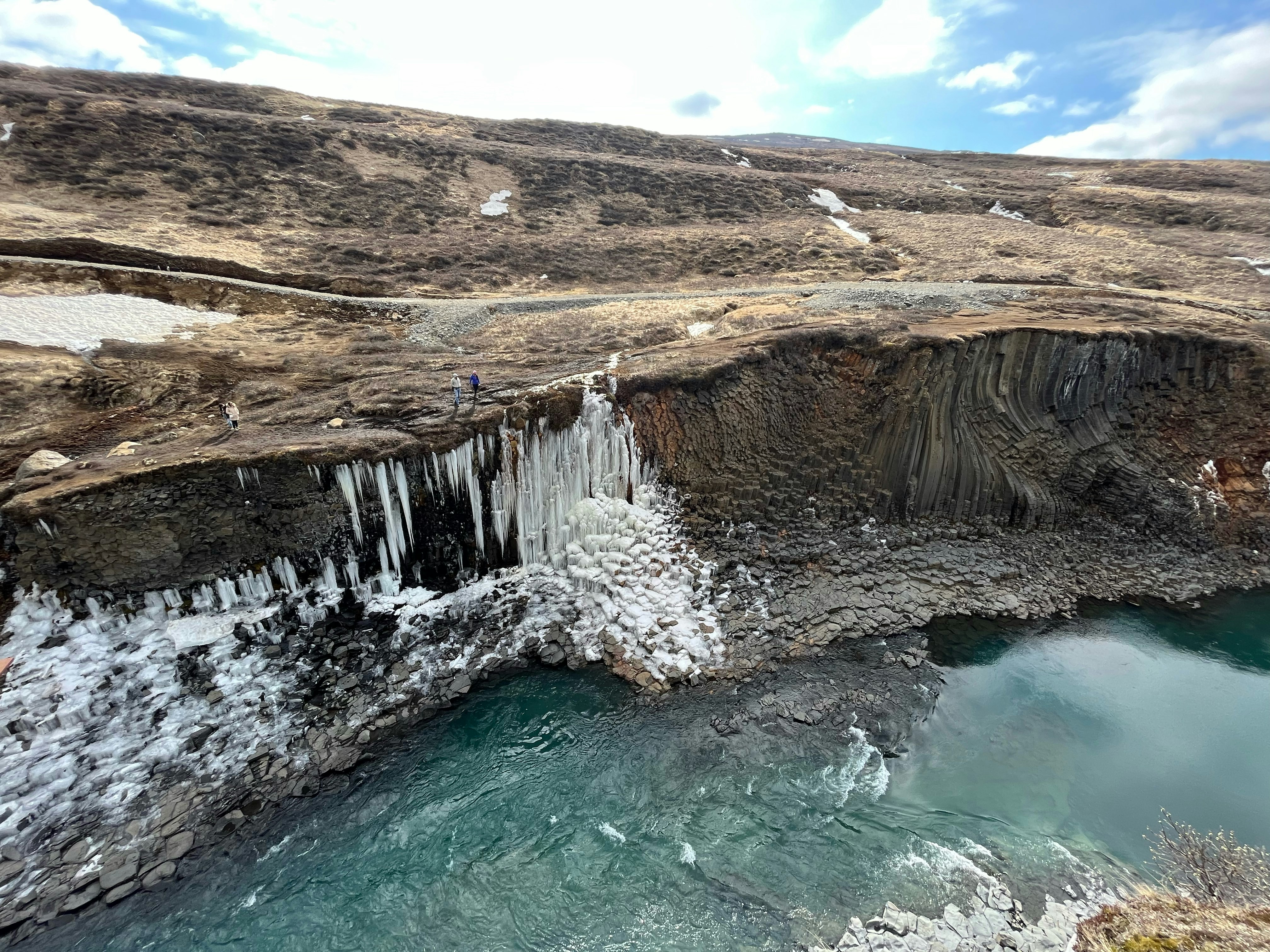 a group of people standing on top of a cliff next to a body of water