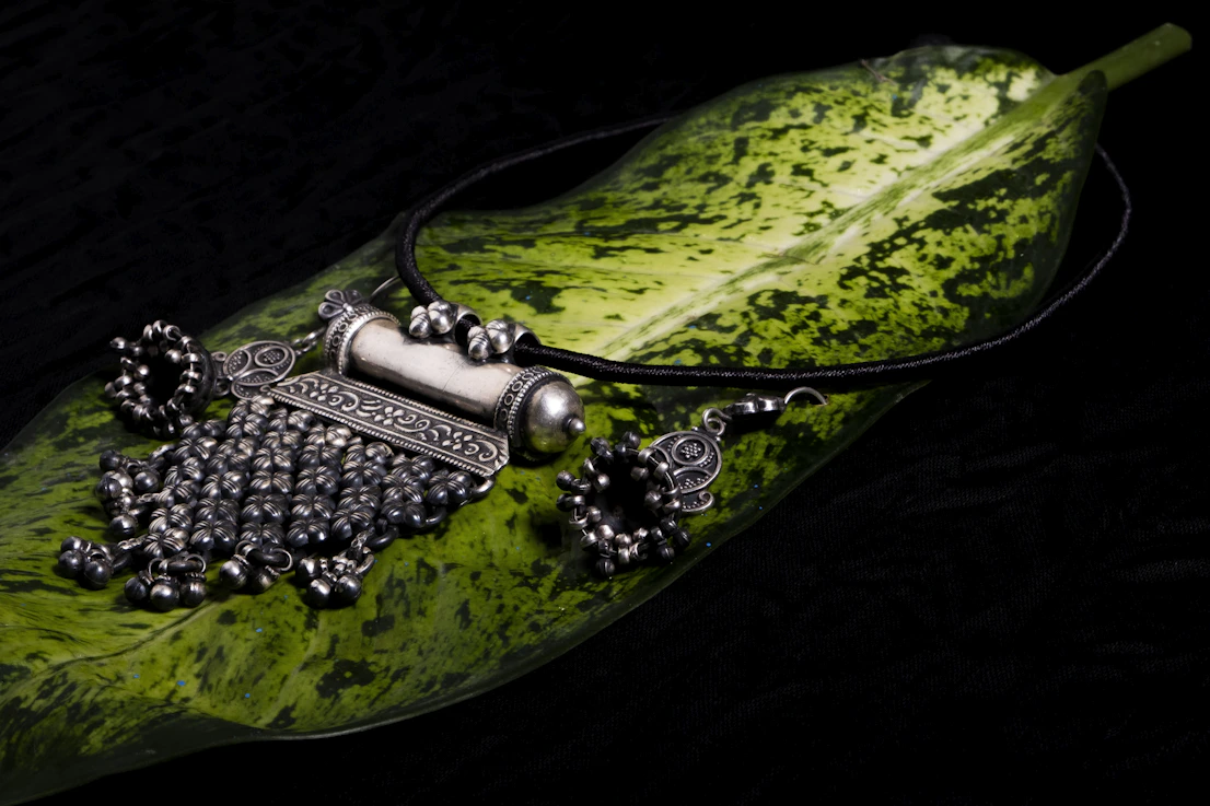 Close-up of a silver necklace inspired by ancient Mexican symbols, sparkling in natural light.