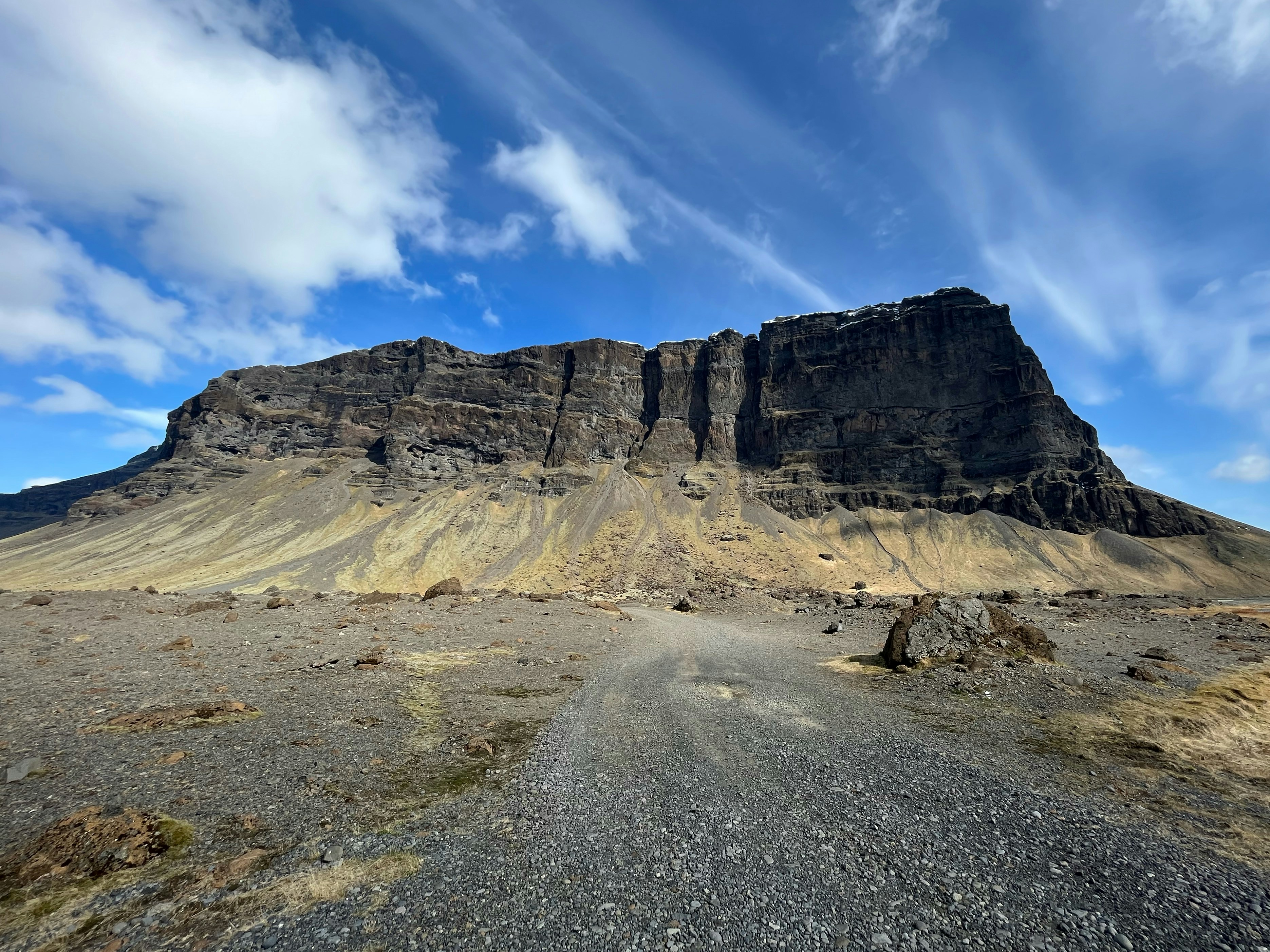 a dirt road with a mountain in the background