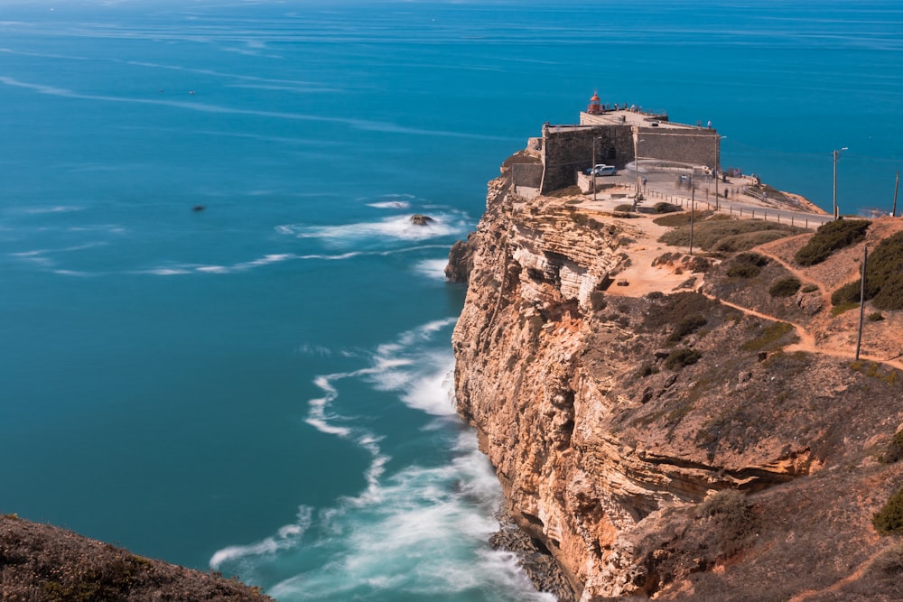 a cliff overlooking a body of water with a castle on top