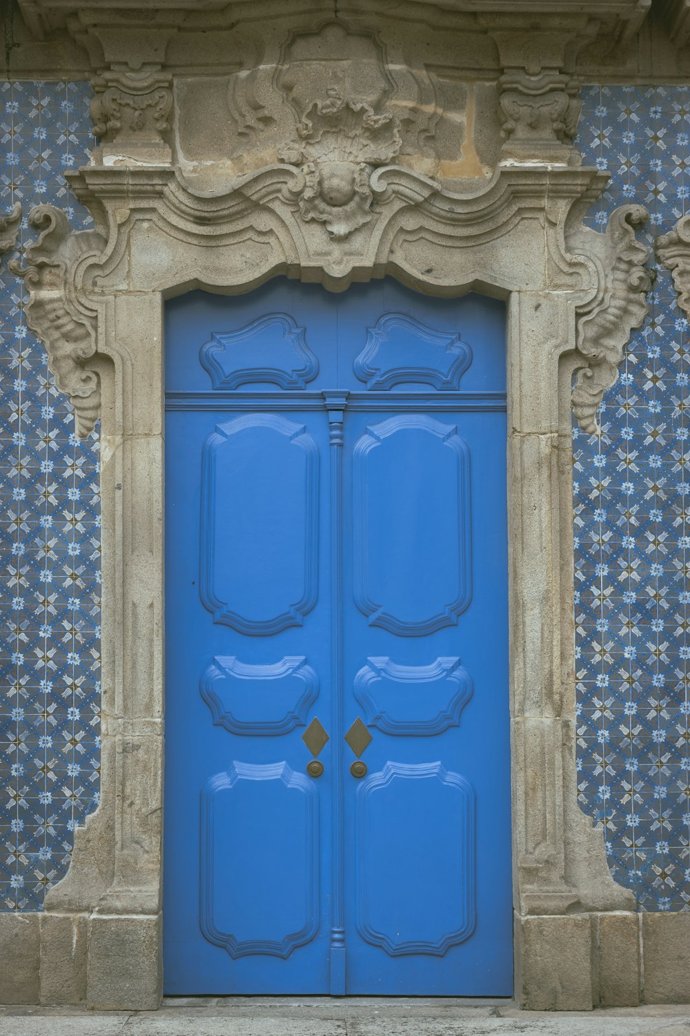 a blue door with ornate carvings on the side of a building