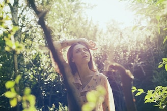 a woman standing in a forest with her hands on her head