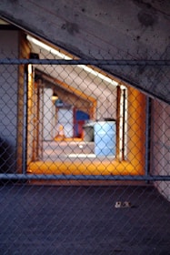 Wide shot of the factory floor showing machines producing chain link fences with orange and gray tones.