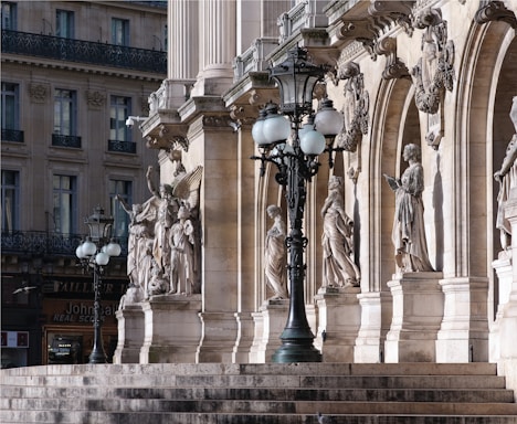 a lamp post in front of a building with statues on it