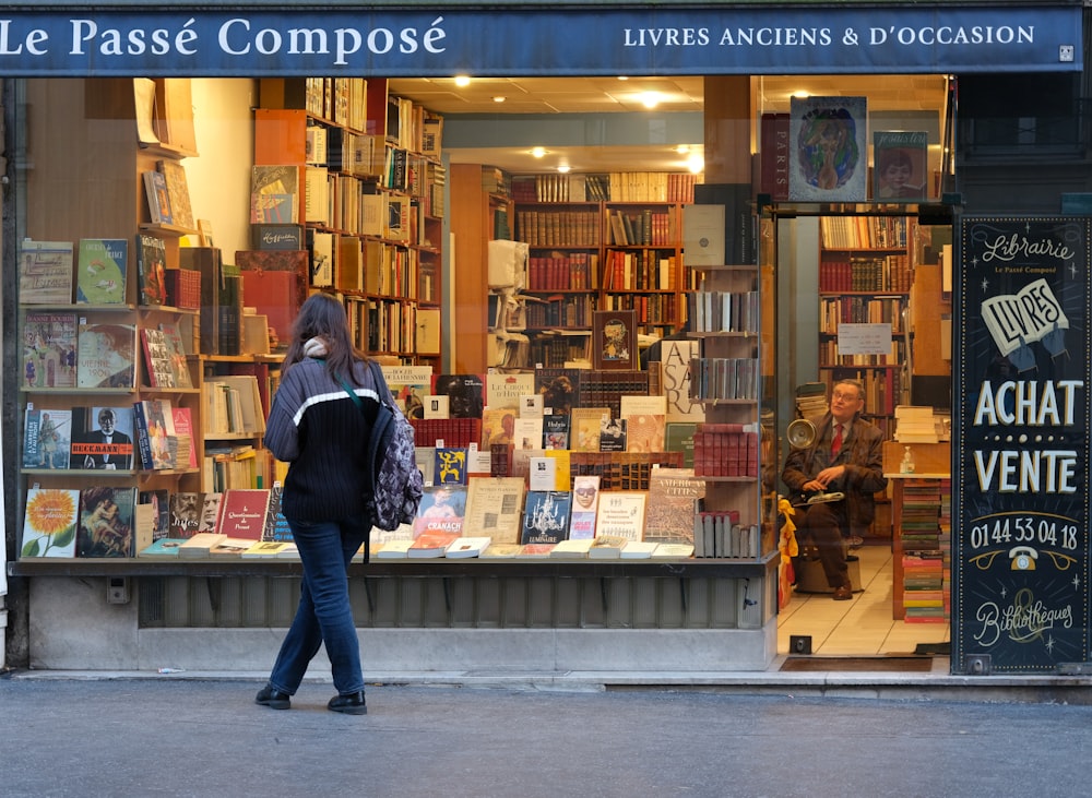 a woman is walking past a book store