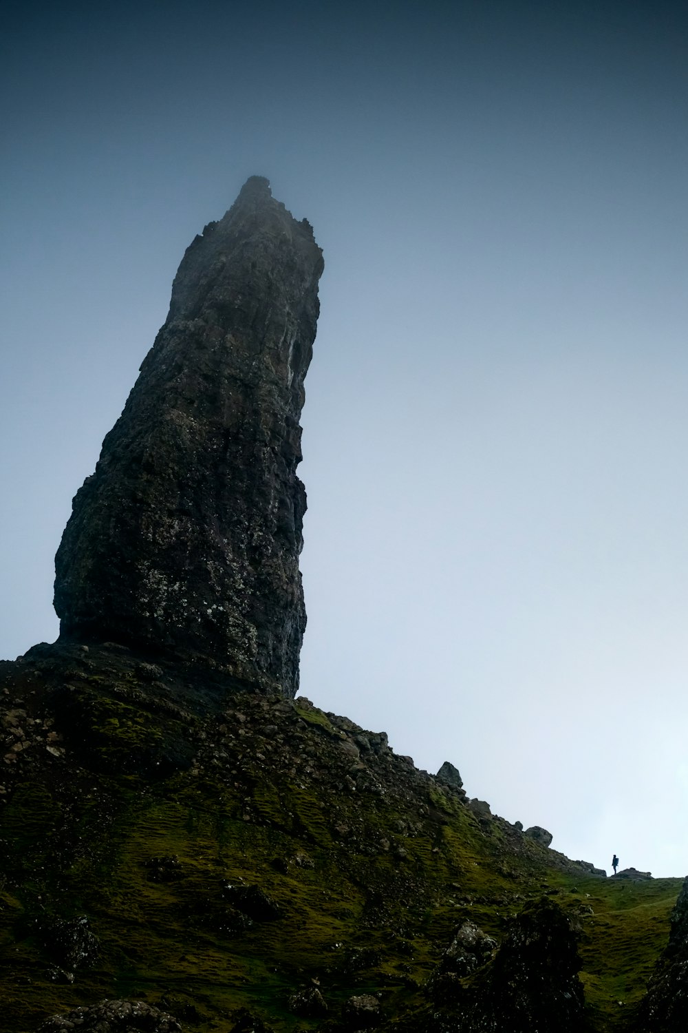 a tall rock sticking out of the side of a hill