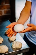 Artisan baker shaping dough in a cozy bakery setting.