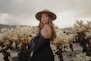 a woman wearing a hat standing in a field of cacti