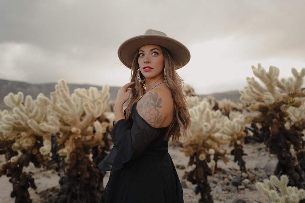 a woman wearing a hat standing in a field of cacti