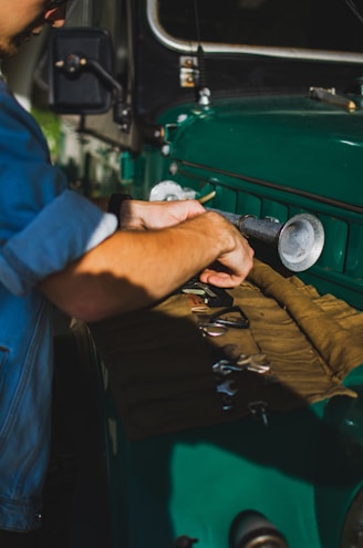 A friendly technician working on an RV parked outdoors with tools spread around.