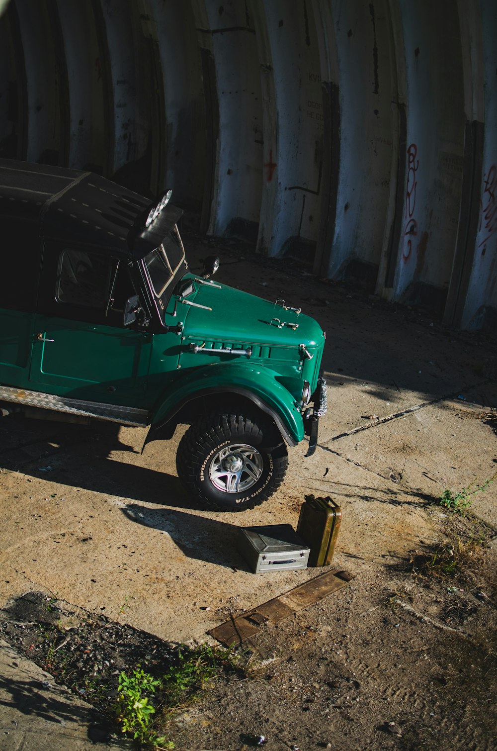 a green jeep parked in front of a tunnel