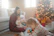 A cozy family gathered around a fireplace, smiling as they use a tablet to plan their holiday elf adventures.