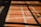 A tiled floor with a red and white grid pattern is partially covered by shadows cast from a window, forming rectangular shapes on the surface.