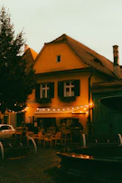 A cozy café patio with string lights glowing softly as evening falls on a small southern town.