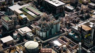 A panoramic view of an industrial oil and gas facility at sunset, highlighting complex pipelines and machinery.