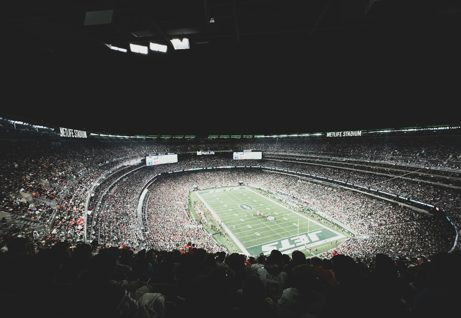A stadium crowd watching a football game from behind the end zone