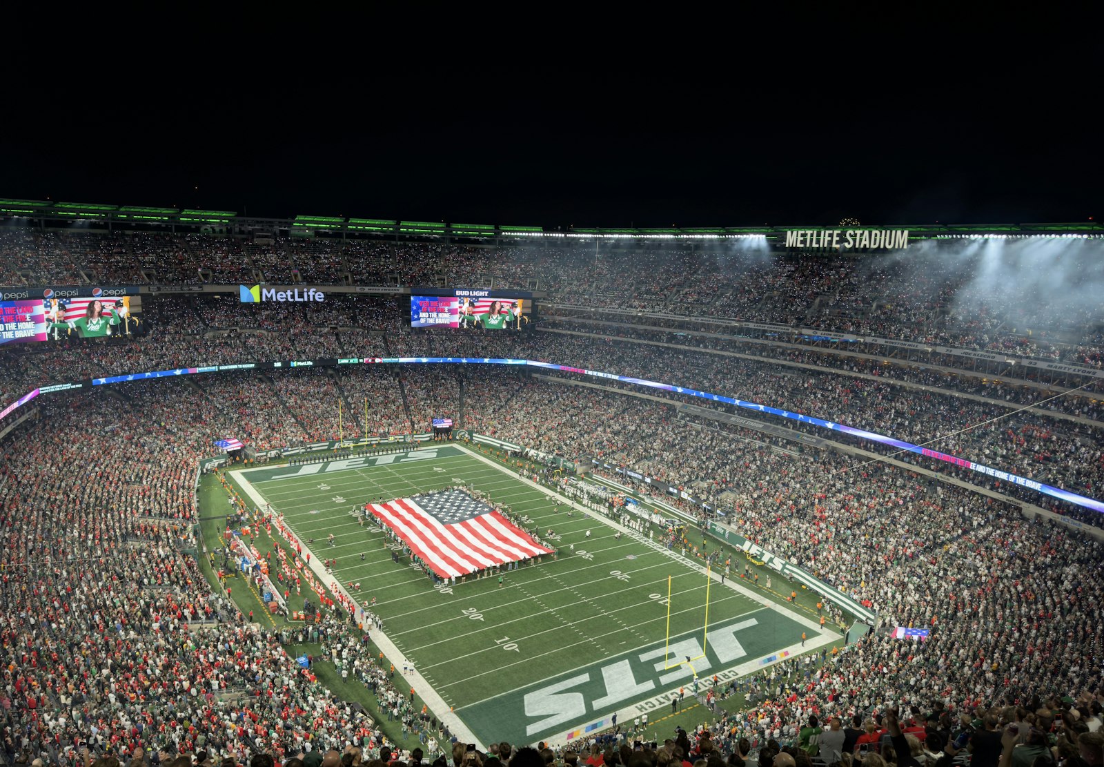 A packed football stadium under the lights at night