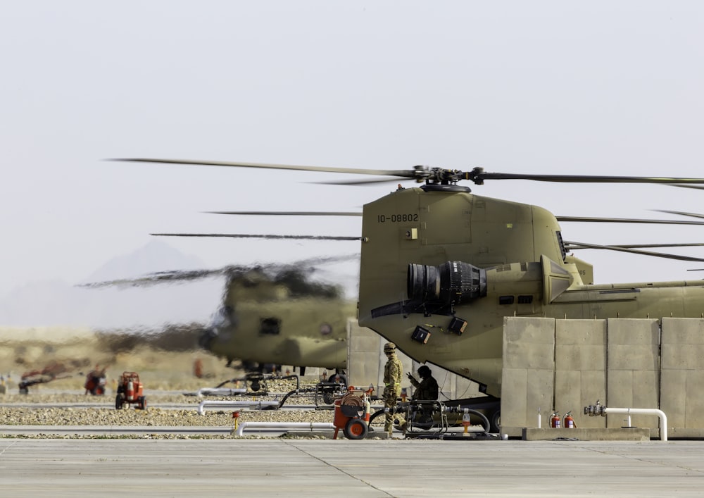 a military helicopter sitting on top of an airport tarmac