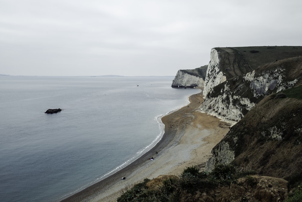 a beach next to a cliff with a body of water
