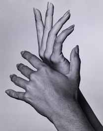 a black and white photo of two hands reaching up