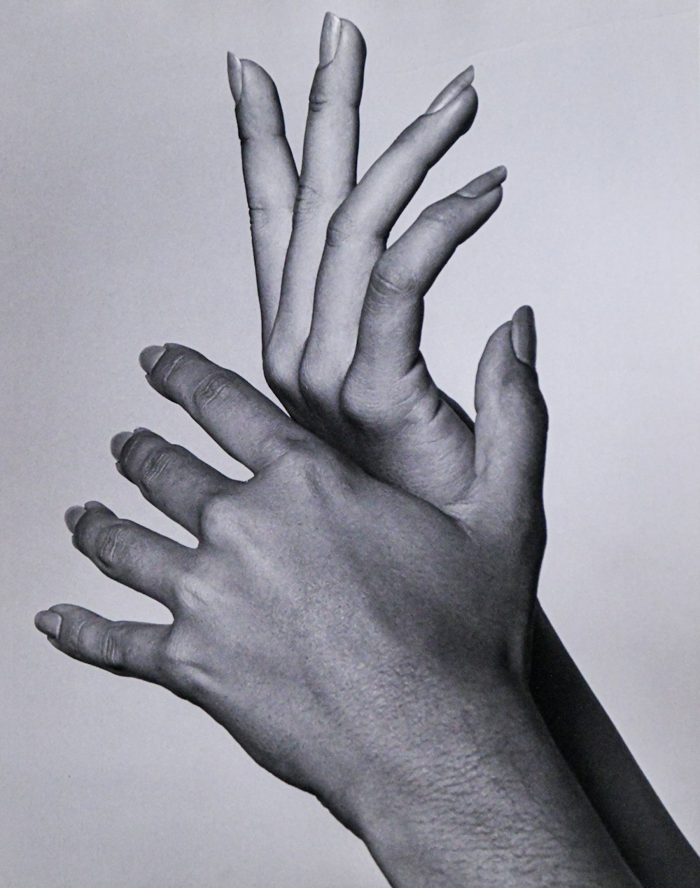 a black and white photo of two hands reaching up