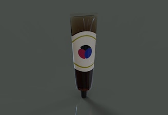 A brown tube, likely cosmetic or medicinal, standing upright against a dark green background. The tube has a label featuring a simple design with a red and blue graphic.