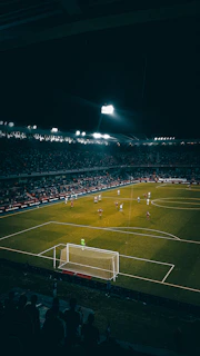 Tense penalty shootout scene under bright stadium lights with focused players and goalkeepers.