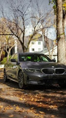 A sleek brown car parked on a quiet street with autumn leaves around.
