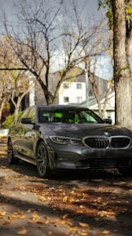 A sleek used sedan parked on a quiet street in Norwood, Massachusetts, with autumn leaves around.