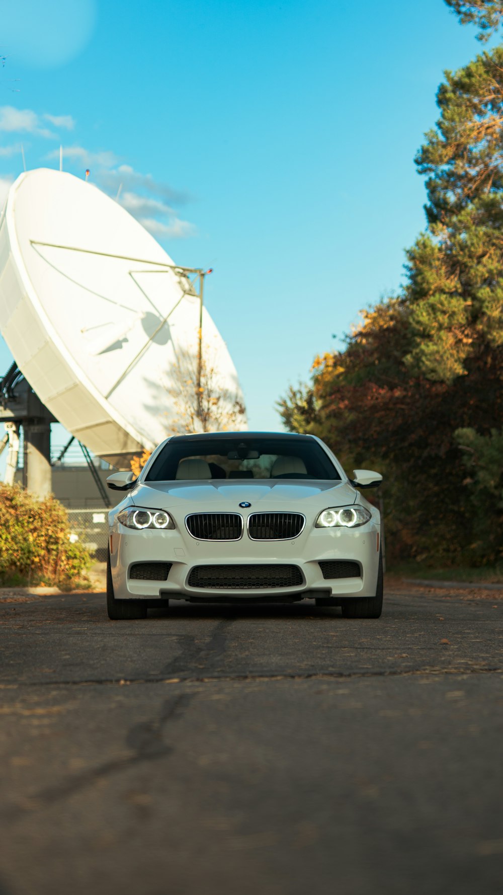 a white car parked in front of a satellite dish