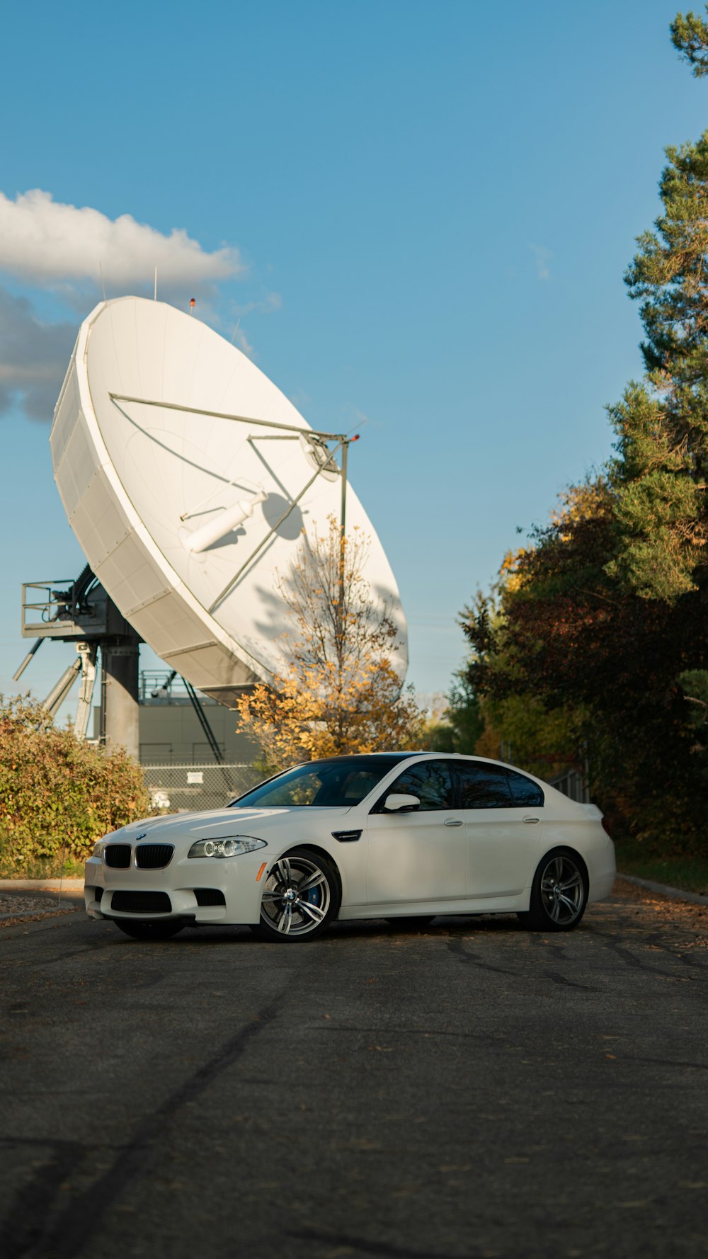 a white car parked in front of a satellite dish