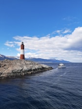 a boat is in the water near a light house