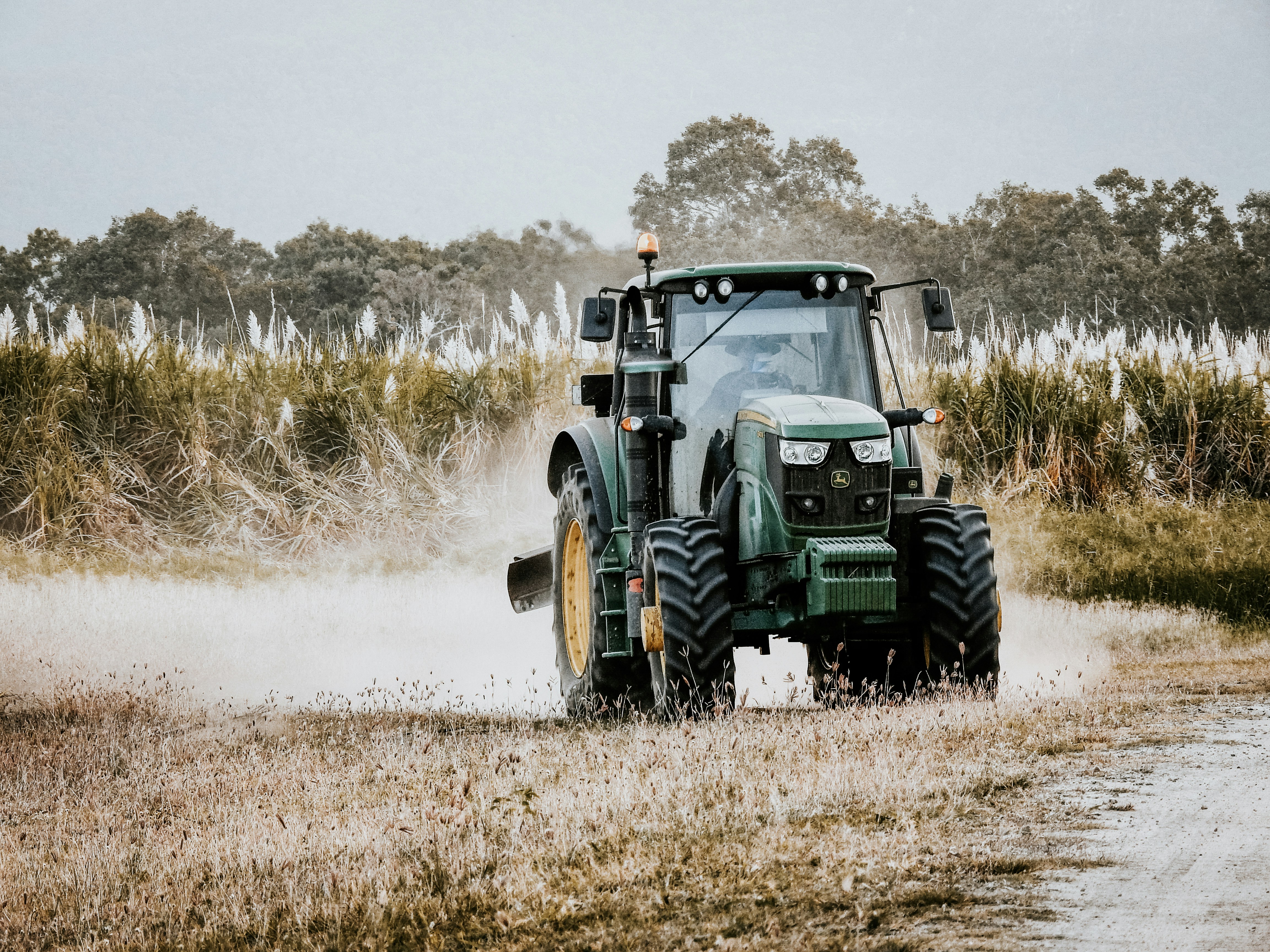 a tractor is driving down a dirt road