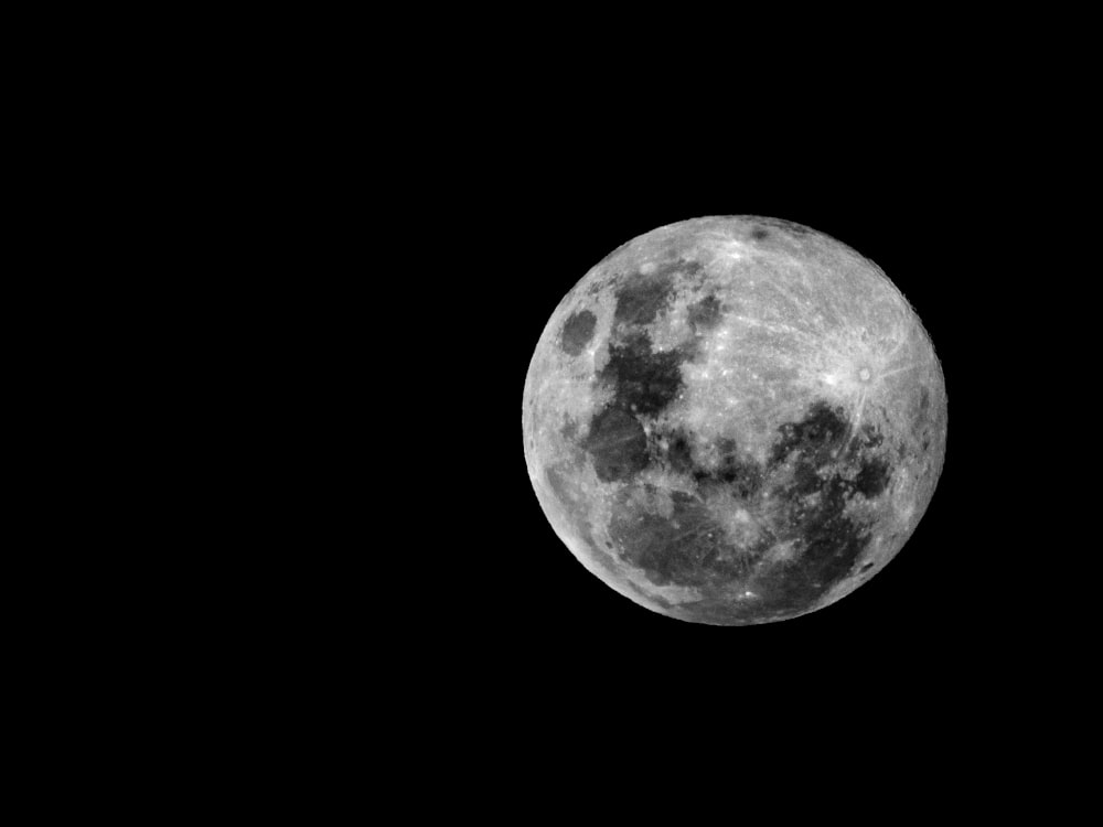 a full moon is seen in the dark sky