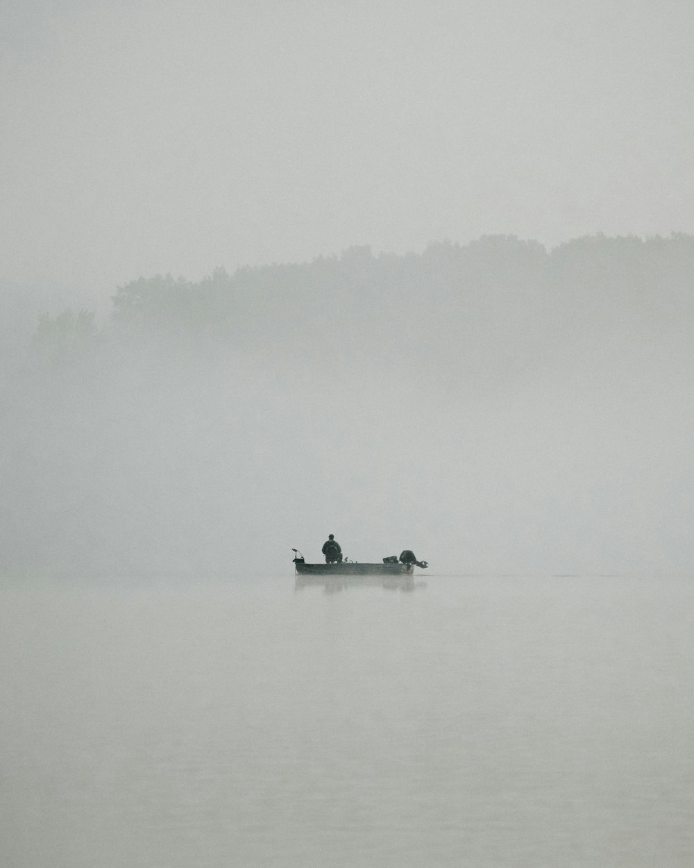 two people in a boat on a foggy lake