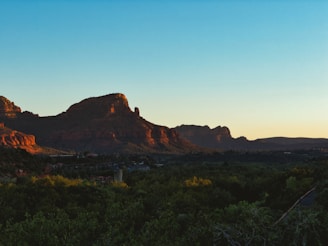 A serene Sedona red rock formation glowing warmly at sunset, framed by native desert plants.
