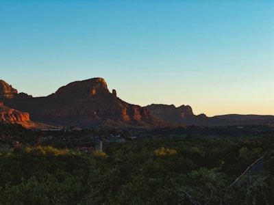 A serene Sedona red rock formation glowing warmly at sunset, framed by native desert plants.