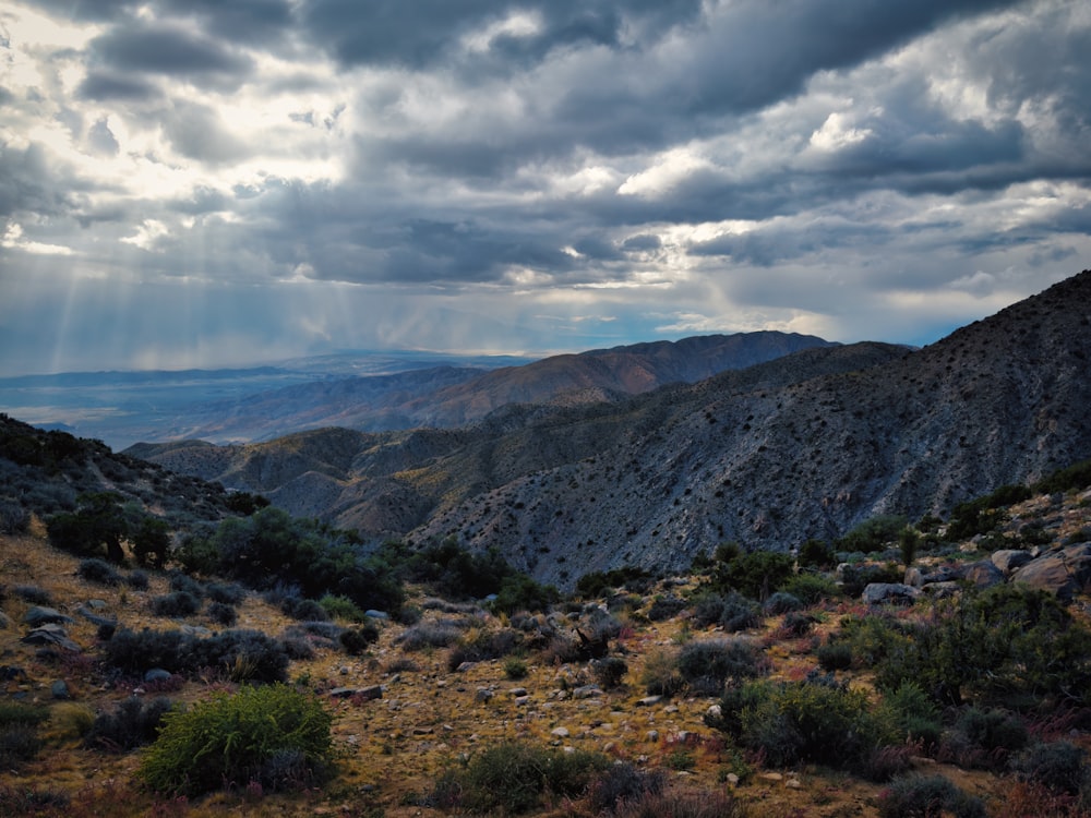 Die Sonne scheint durch die Wolken über den Bergen