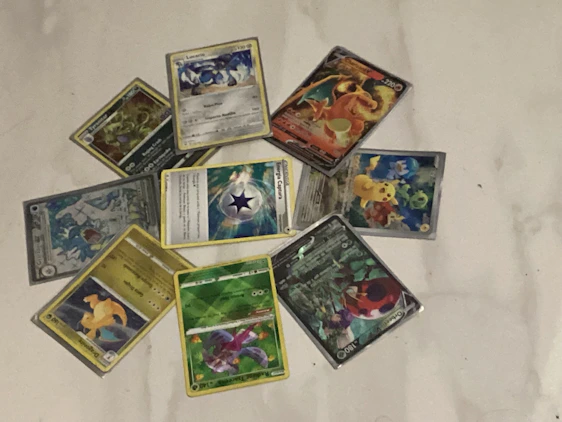 A colorful display of Pokémon cards arranged neatly on a wooden table with warm lighting highlighting their vibrant artwork.