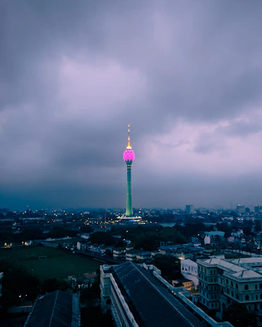 A sleek telecommunications tower glowing with green lights against a night sky.