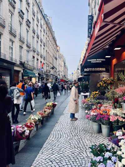 A vibrant high-street retail scene with diverse shops and bustling foot traffic under a clear sky.
