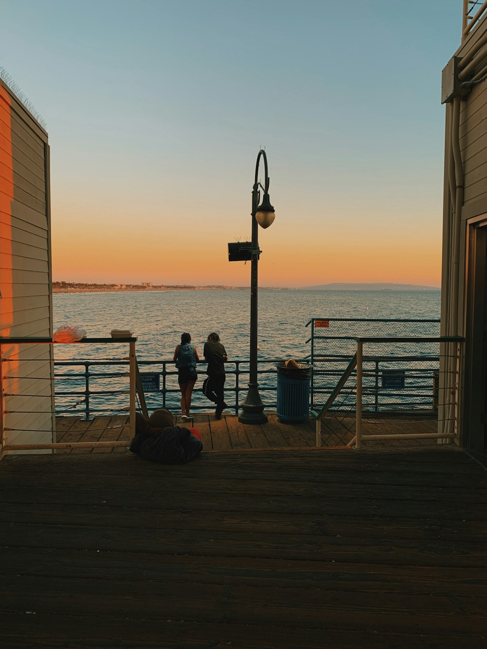 a couple of people standing on top of a pier