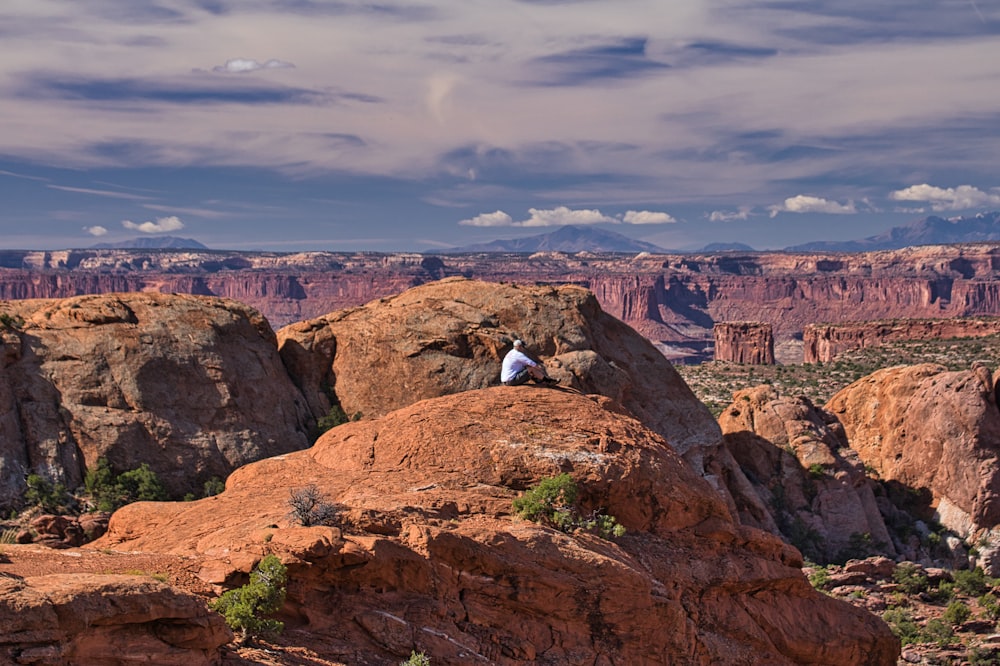 a person sitting on top of a large rock