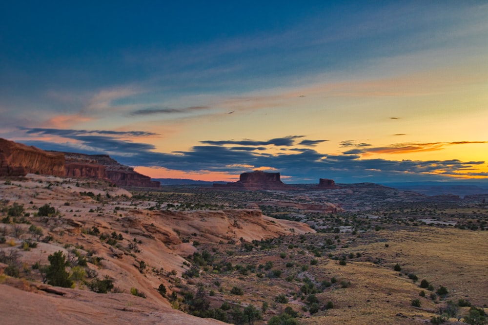 the sun is setting over the desert landscape