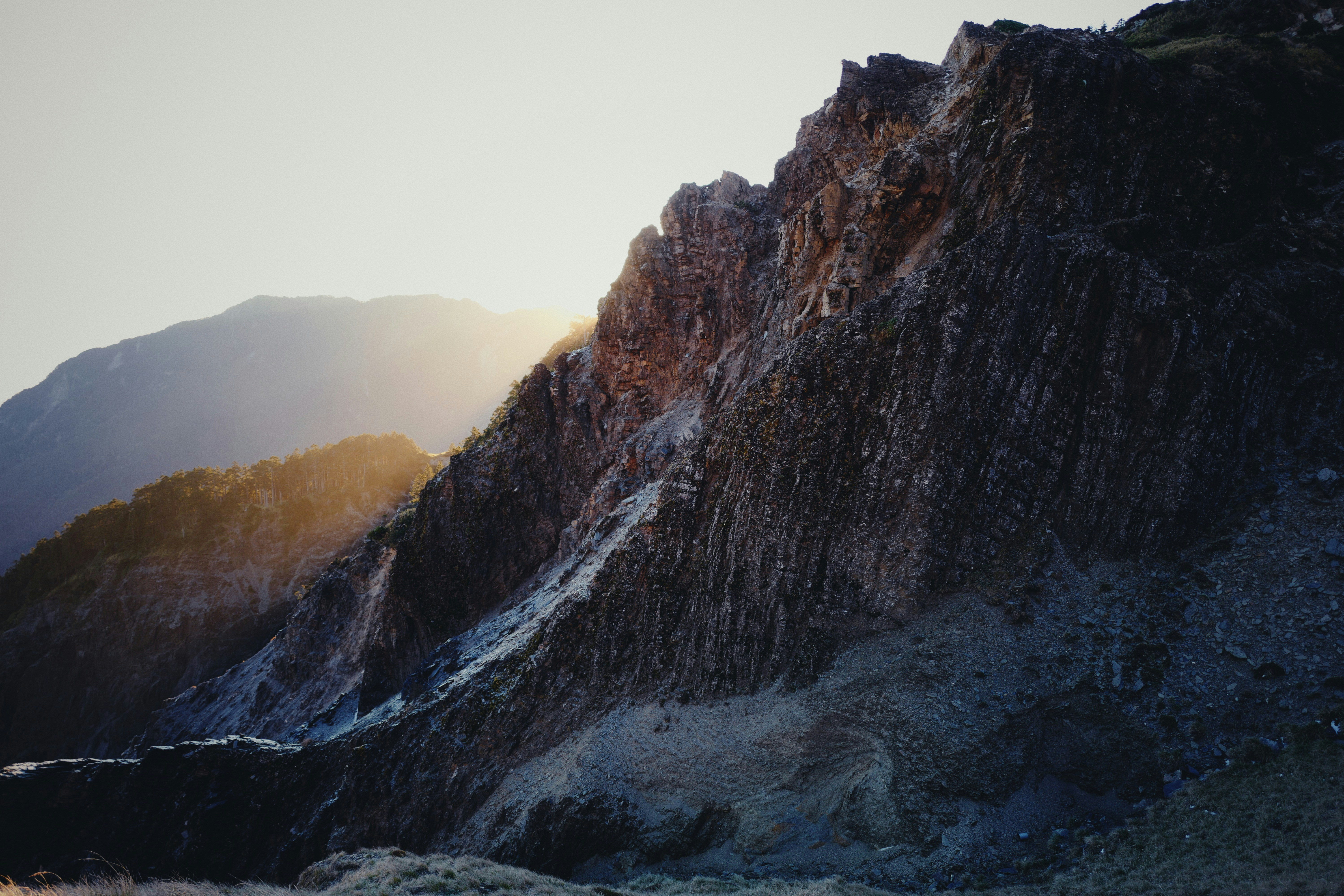 the sun is shining on a rocky mountain