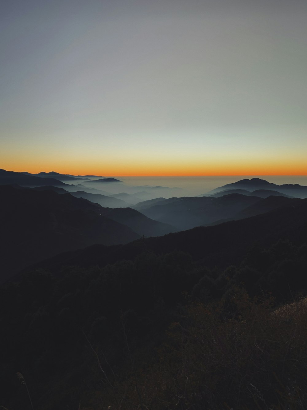 the sun is setting over a mountain range