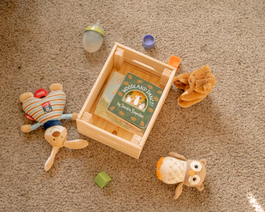 a wooden box with two stuffed animals on the floor