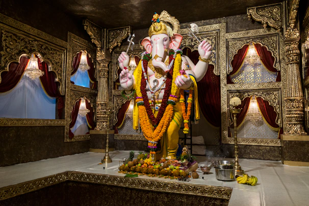 Elegant brass Ganesh statue adorned with a red cloth and fresh flower garlands in a home altar.
