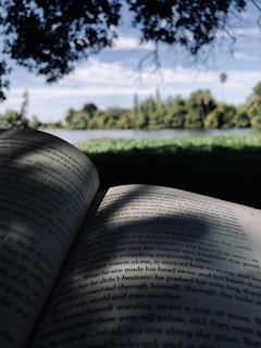 an open book sitting on top of a lush green field
