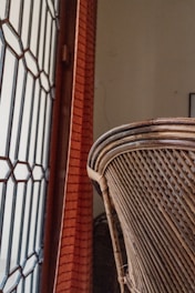 a close up of a wicker chair near a brick wall